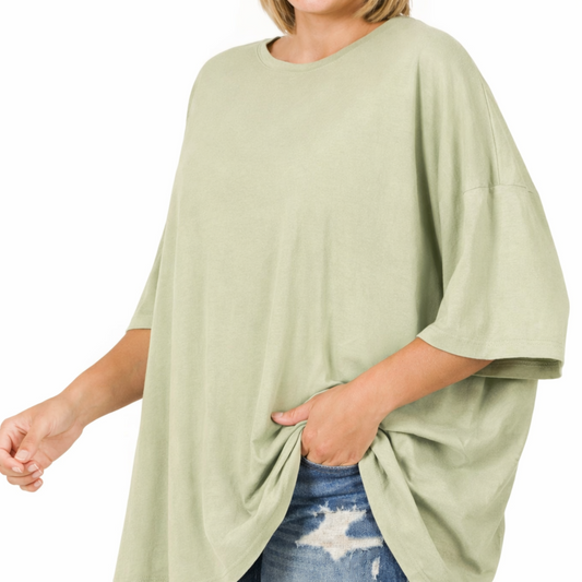 Person wearing a light green oversized shirt with blue jeans on a white background