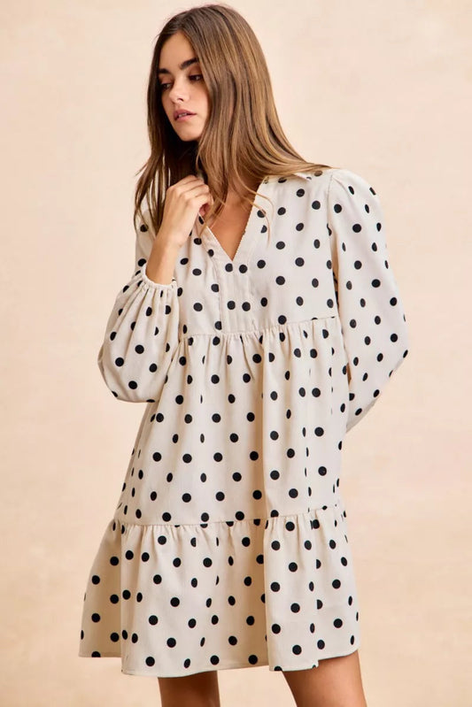 Cream polka dot baby-doll mini dress with black dots, long puff sleeves, tiered skirt, and lightweight flowy fit for everyday wear