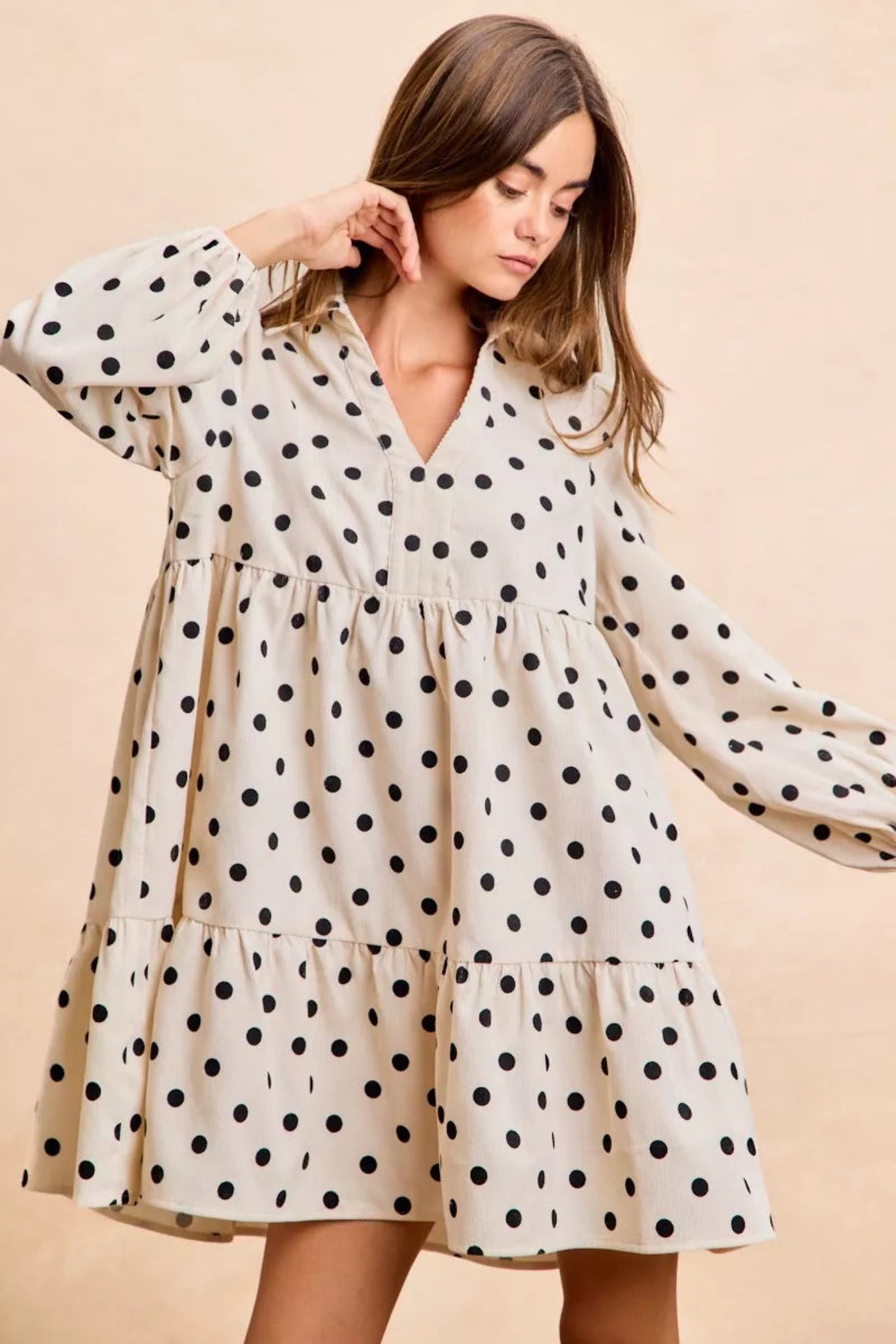 Cream polka dot baby-doll mini dress with black dots, long puff sleeves, tiered skirt, and lightweight flowy fit for everyday wear