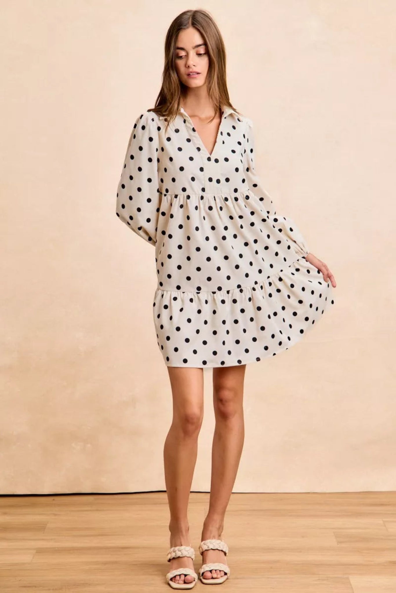Cream polka dot baby-doll mini dress with black dots, long puff sleeves, tiered skirt, and lightweight flowy fit for everyday wear