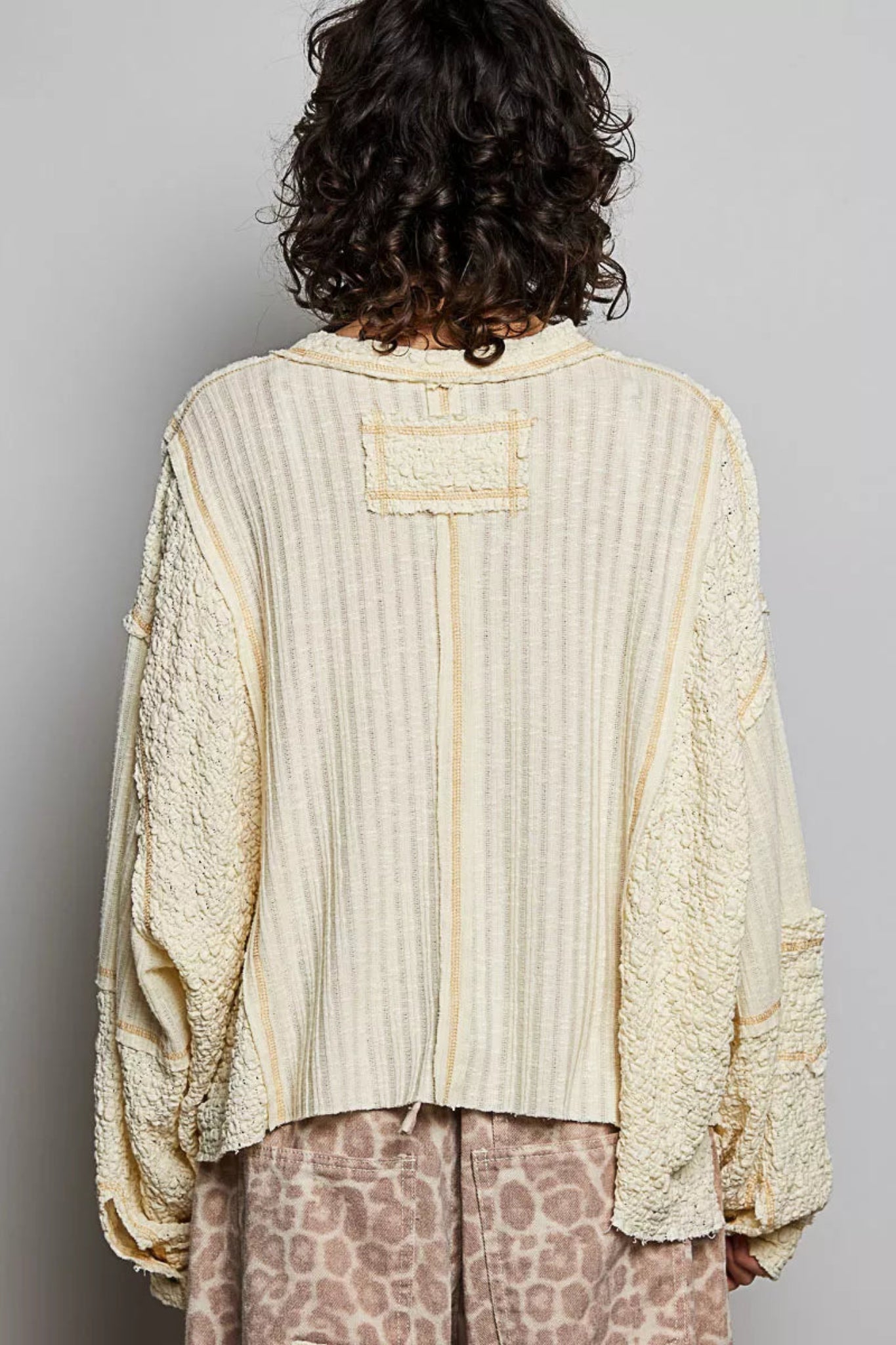 POL women’s cream textured V-neck oversized long sleeve top with raw seam detail and mixed fabric panels