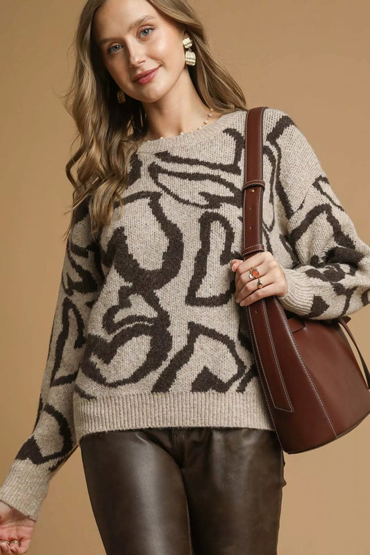 Latte beige abstract print knit sweater with crew neckline and long sleeves on a model against a neutral background