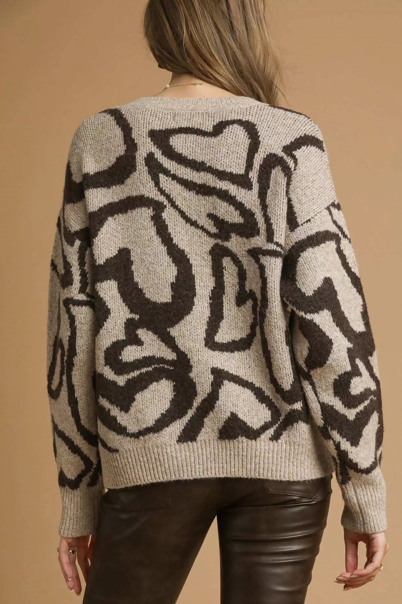 Latte beige abstract print knit sweater with crew neckline and long sleeves on a model against a neutral background