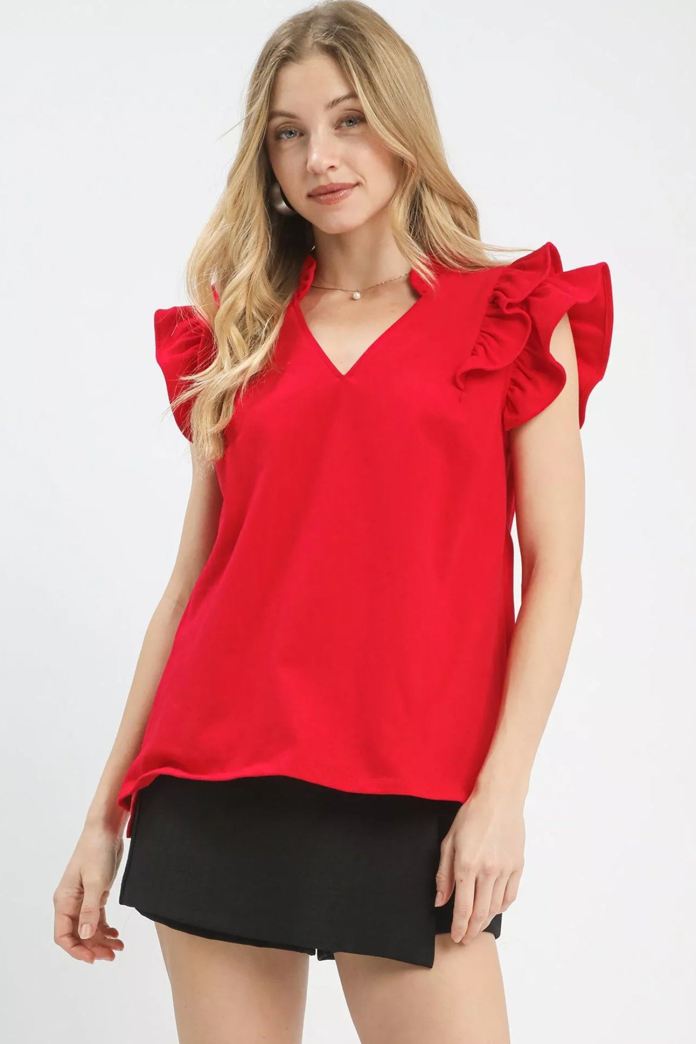 Cherry red ruffle sleeve v-neck blouse with flutter shoulders and flowy fit on a model against a white background