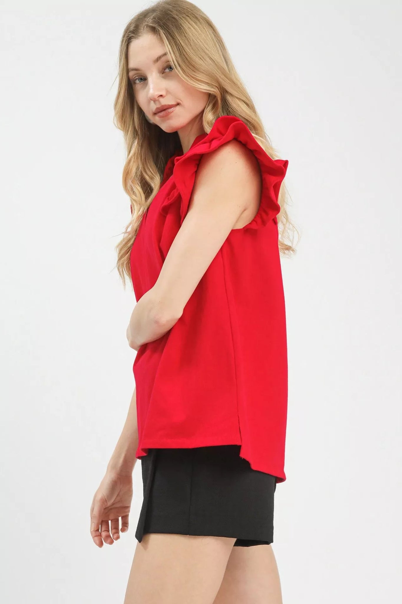 Cherry red ruffle sleeve v-neck blouse with flutter shoulders and flowy fit on a model against a white background