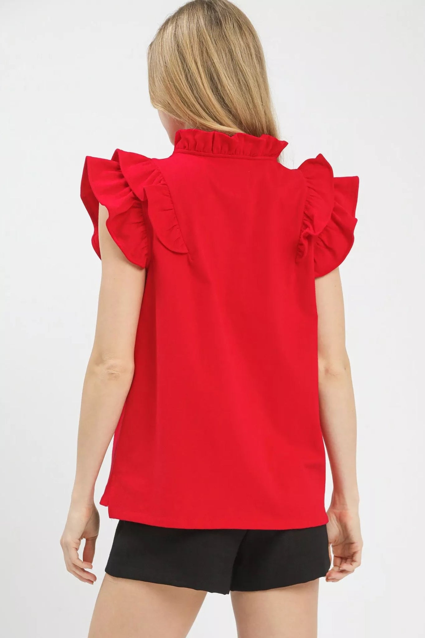 Cherry red ruffle sleeve v-neck blouse with flutter shoulders and flowy fit on a model against a white background