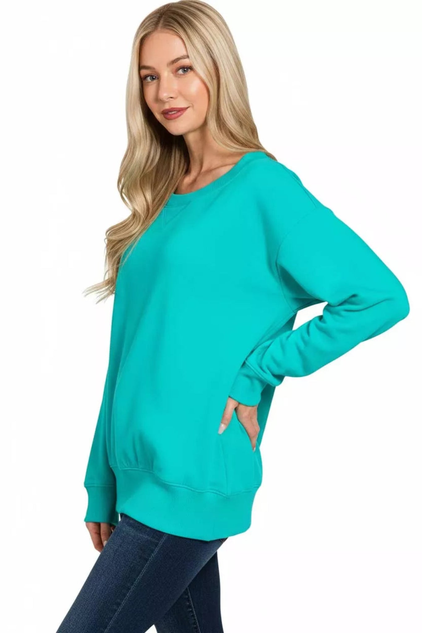 Woman wearing a turquoise long sleeve boat neck sweatshirt with relaxed fit, ribbed cuffs and hem, casual everyday pullover top.