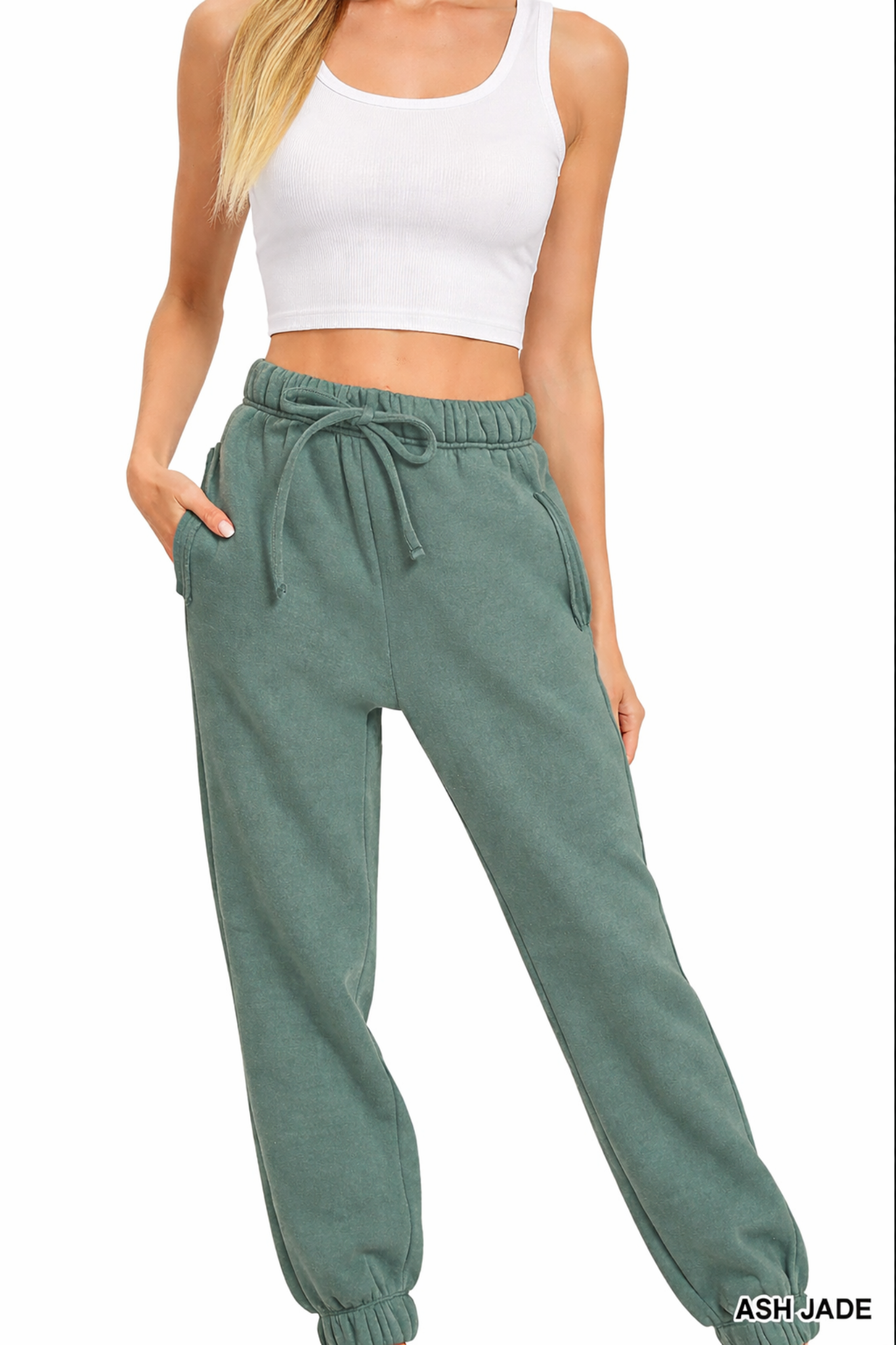 Model wearing ash jade jogger sweatpants with elastic waistband, drawstring tie, side pockets, and cropped white tank top.