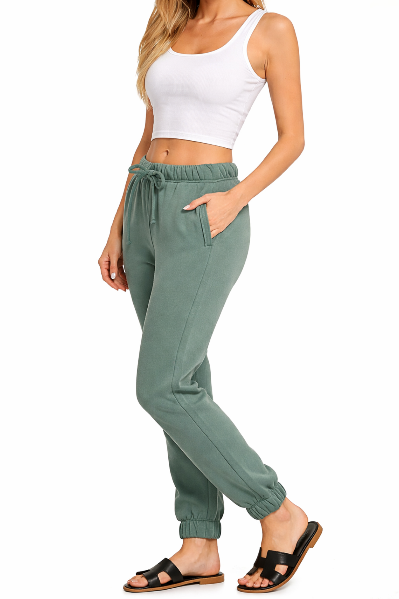 Model wearing ash jade jogger sweatpants with elastic waistband, drawstring tie, side pockets, and cropped white tank top.