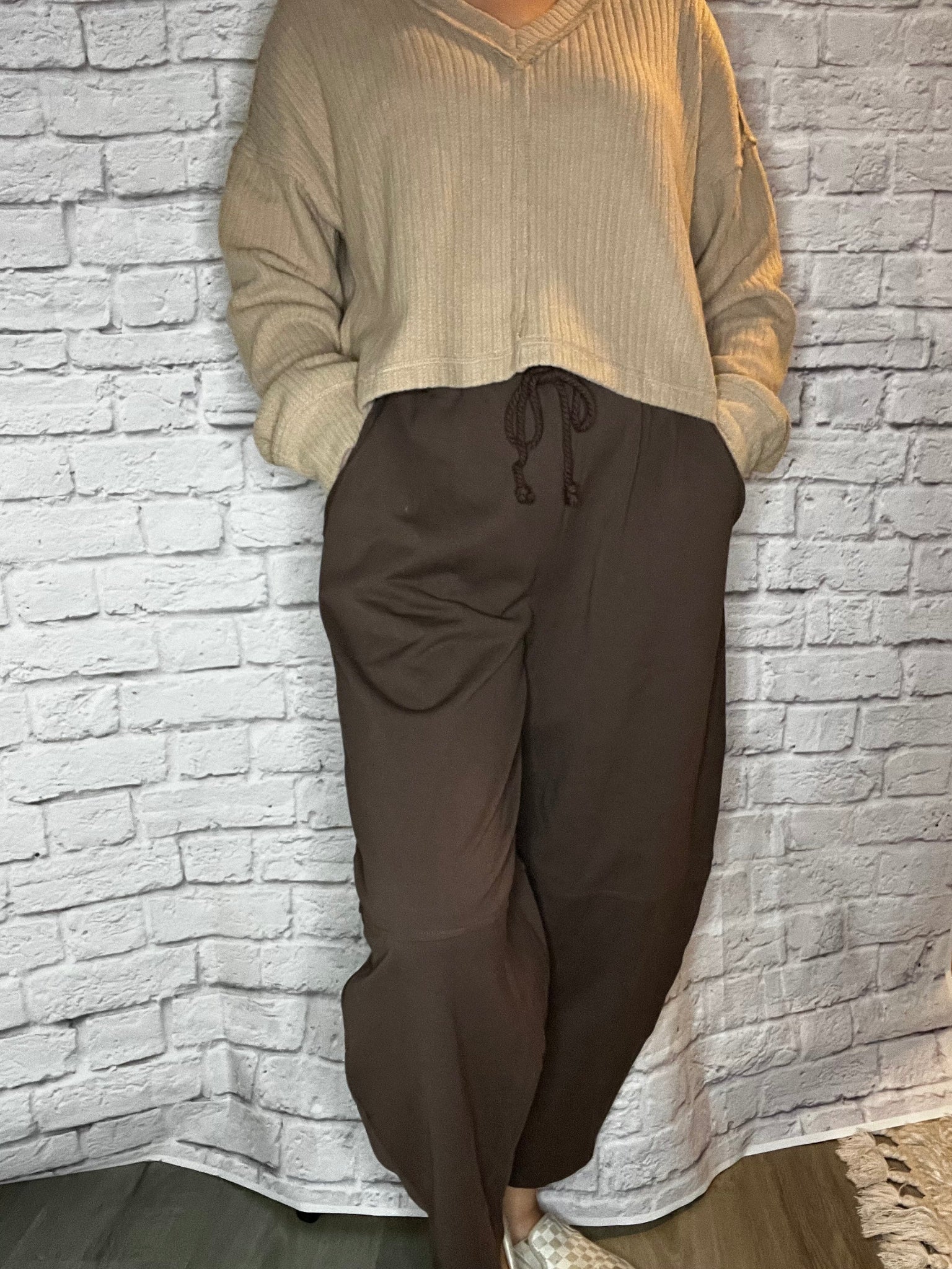 A woman wearing loose-fit brown drawstring pants with wide legs and side pockets