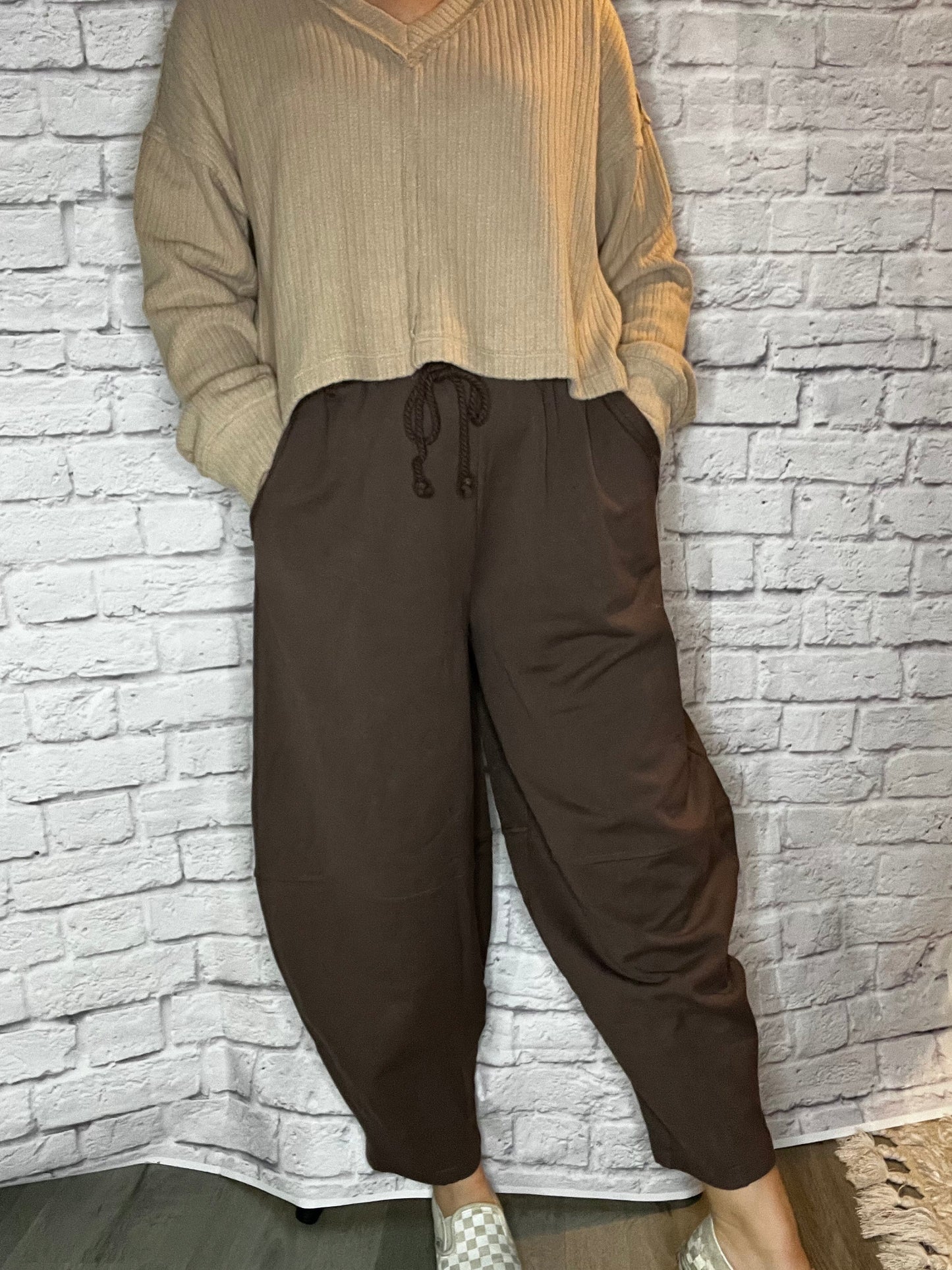 A woman wearing loose-fit brown drawstring pants with wide legs and side pockets