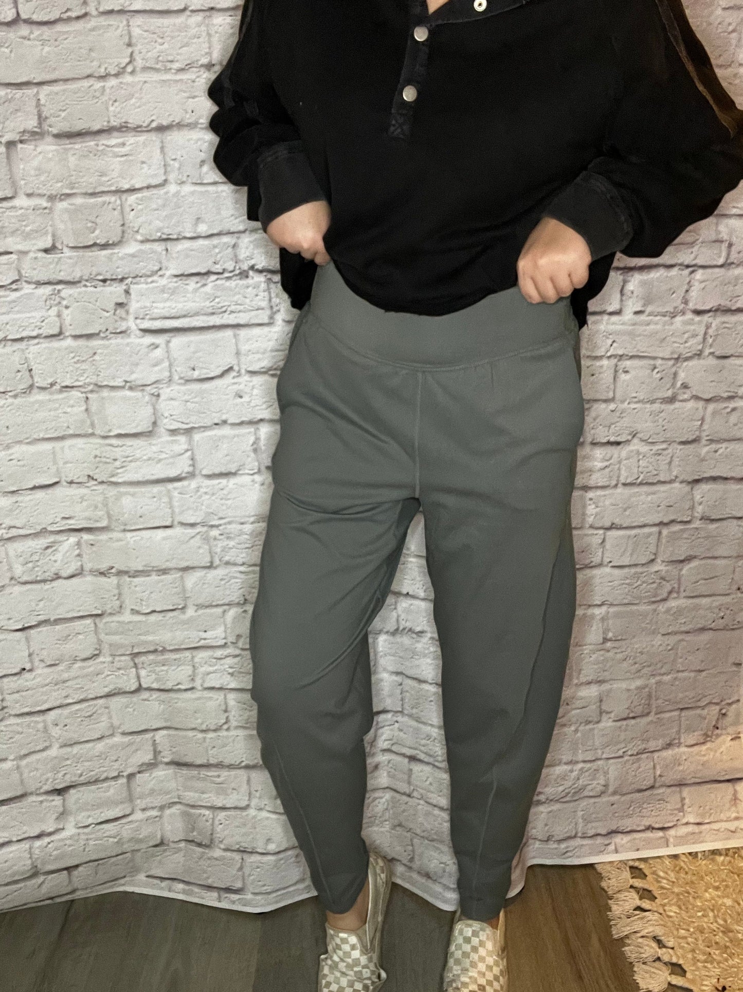 A woman wearing high-waisted gray jogger-style pants with a tapered leg and smooth waistband.