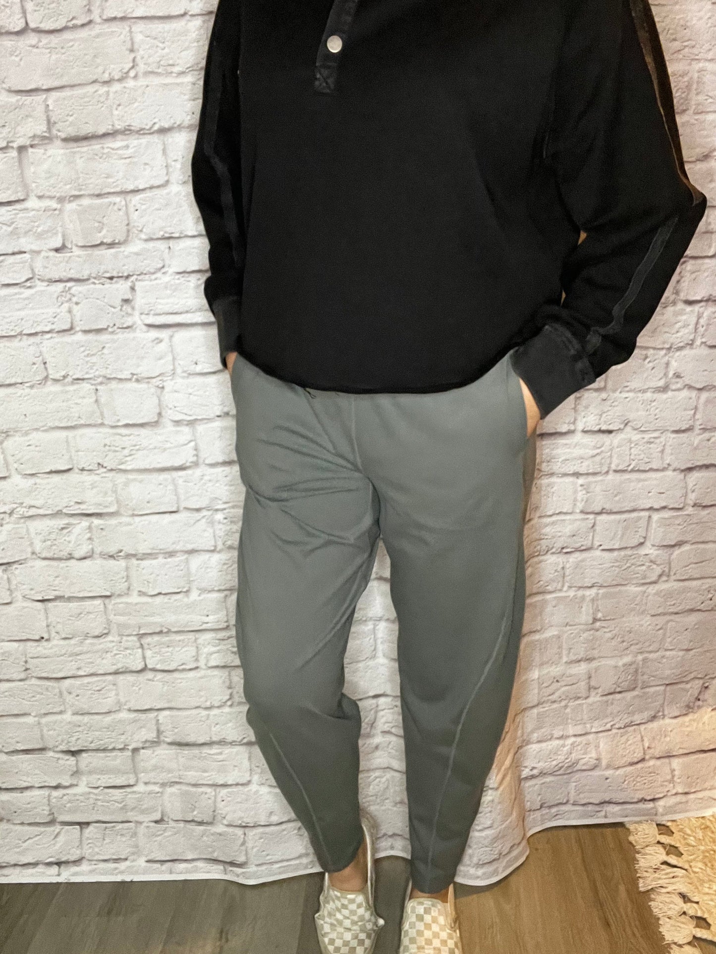 A woman wearing high-waisted gray jogger-style pants with a tapered leg and smooth waistband.