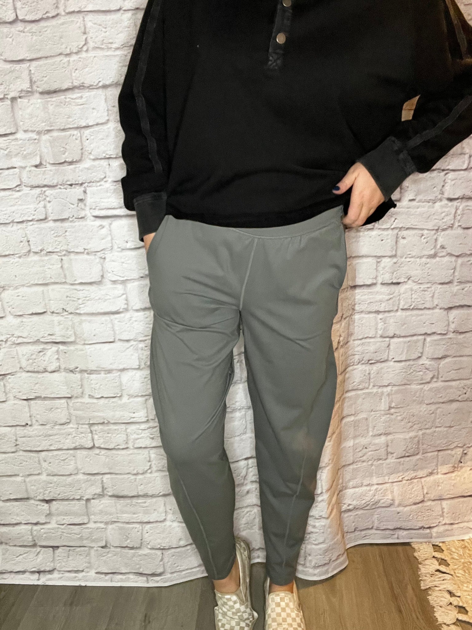 A woman wearing high-waisted gray jogger-style pants with a tapered leg and smooth waistband.