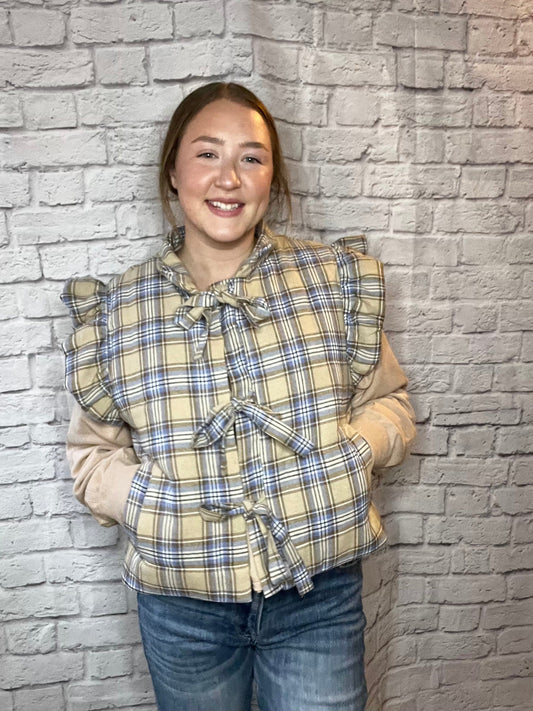 Cozy plaid puffer vest with ruffled shoulders and three front tie closures in beige, blue, and cream tones.